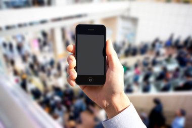 Kentsel arka planda boş ekranlı akıllı telefonu tutan kişinin kırpılmış görüntüsü