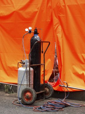 Dışarıdaki karmaşık kabloların yanında duran kaynak tüpleri.