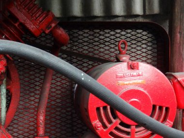 Metal ağ arka planına karşı kırmızı endüstriyel makine parçalarını gösteren yakın plan