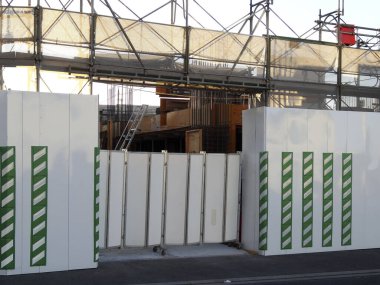 İnşaat sahasında bina iskelesi ve çevresindeki güvenlik engelleri var.