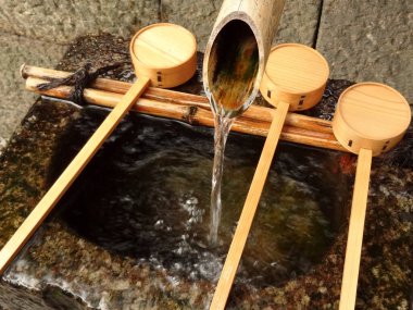 Bambu borusu, yakındaki tahtadan kepçelerle taştan havzaya su döker.