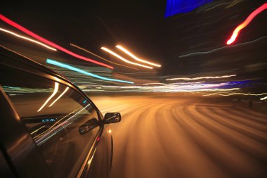 Gece yolundaki arabanın hareket bulanık görüntüsü ve ışık yolları, uzun pozlama 