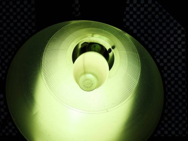 Karanlık duvarın arka planındaki parlak ampulün yakın plan görüntüsü. 