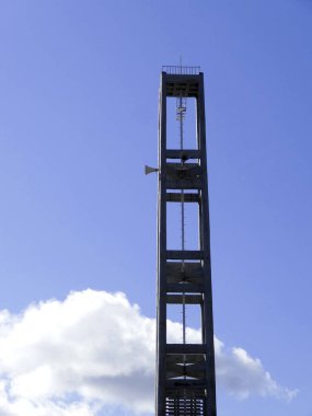 Mavi gökyüzü arka planında duran uzun metal çan kulesi