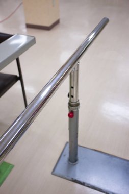 Parlak fayanslı hastane zemininin yanında duran metal korkuluklar.