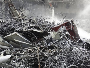 Beton molozların arasına dağılmış bükülmüş metal enkazı.