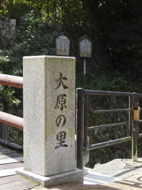 Açık havada metal parmaklıkların yanında Japon kanjisi olan taş sütun.