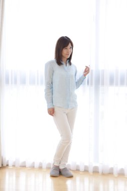 Güzel Asyalı kadın modern dairede duruyor. 