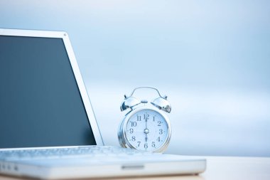 Gece gökyüzü arkaplanında saati olan dizüstü bilgisayar