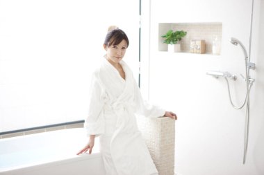 Banyoda bornozlu güzel bir Asyalı genç kadın.