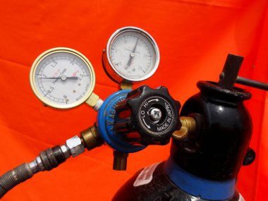 Yakından bakınca parlak turuncu arkaplana karşı gaz silindiri basınç göstergeleri görülüyor