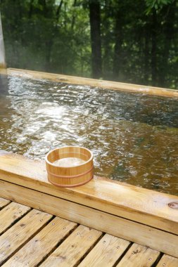 Ağaçlarla çevrili ahşap jakuzi ve yükselen buhar