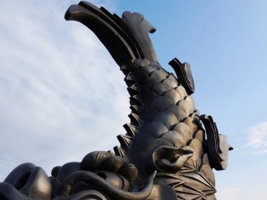 Mavi gökyüzü arka planında yükselen siyah ejderha heykeli