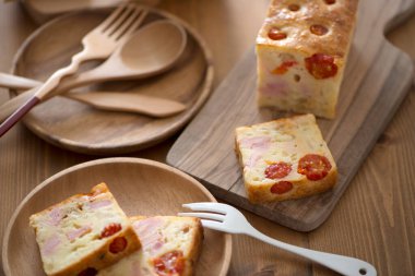 Mutfak masasında peynirli, jambonlu ve sebzeli lezzetli ev yapımı ekmeğin yakın plan görüntüsü.        