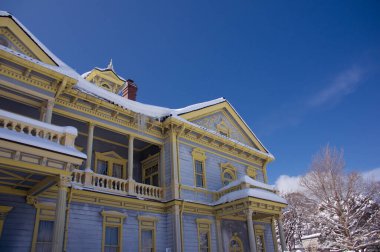 Mavi gökyüzünün altında karla kaplı Viktorya dönemi evi