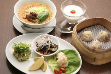 Konforlu bir restoran ortamında canlı renkleri ve dokuları olan bir masada servis edilen lezzetli Asya yemekleri.