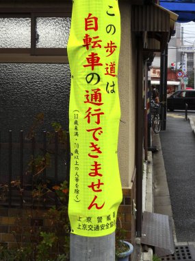 Kaldırımın kenarında asılı parlak sarı Japon tabelası