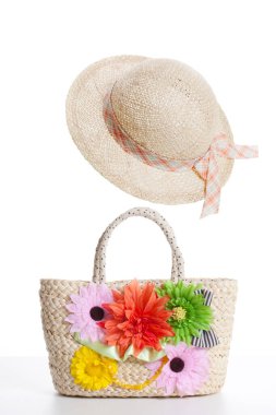 Çiçeklerle süslenmiş hasır şapka beyaz arka planda izole edilmiş hasır sepet. 