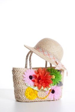 Çiçeklerle süslenmiş hasır şapka beyaz arka planda izole edilmiş hasır sepet. 