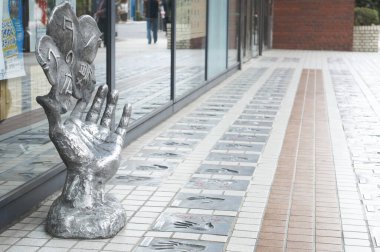 Açık bir günde modern bir alışveriş merkezinin yanındaki yansıtıcı el heykeli