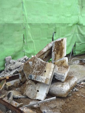 Kırık beton bloklar yeşil inşaat brandasına dayanır