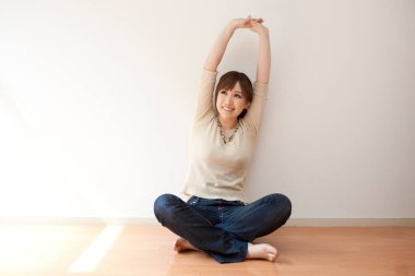 Japon kadın boş odada yerde oturuyor.