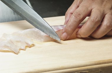 Keskin bir bıçakla çiğ balık filetosu dilimliyorum.