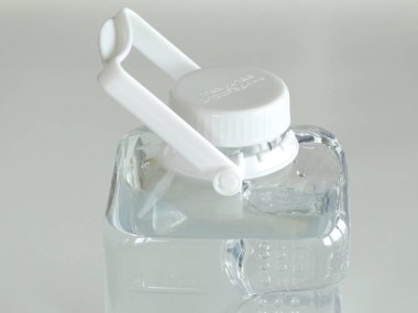 Şeffaf kabın içinde beyaz kapaklı temiz sıvı var.