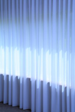 Evdeki penceresinde gölgesi olan mavi perde. 