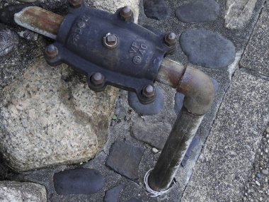 Paslı metal boru eski taş kaldırımlara bağlanıyor.