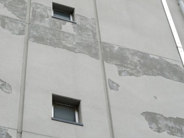 Yıpranmış beton bina cephesi camların etrafını boyuyor.