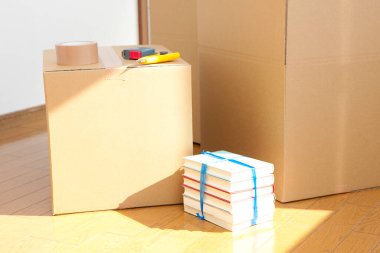 Yeni dairedeki karton kutunun üzerindeki alet edevat ve kitaplar.      