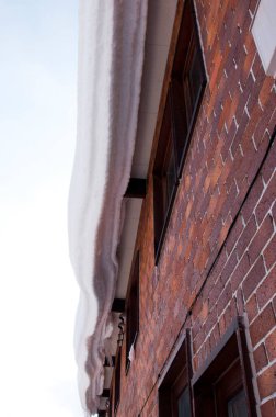 Yoğun kar kırmızı tuğla bina pencerelerinin üzerinde tehlikeli bir şekilde asılı.