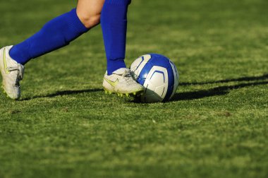 Spor giyim sektöründe futbol oyuncusunun bacakları çimlerin üzerinde top oynuyor.                 