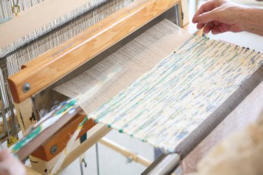 Geleneksel dokuma tezgahında renkli kumaşlar ören eller