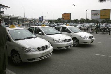 Havaalanı kaldırımına park edilmiş üç beyaz taksi.