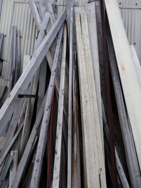 Yığılmış metal kirişler bükülmüş sanayi duvarına yaslanıyor.