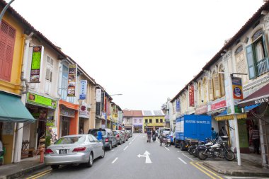 Renkli dükkanlar ve park edilmiş araçlarla dolu bir cadde.