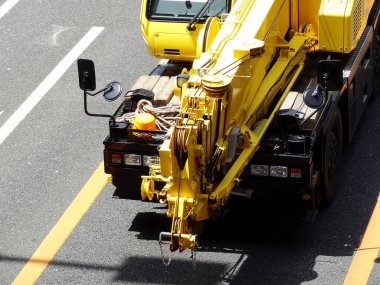 Sarı vinç kamyonu şehir caddesinde park halinde.