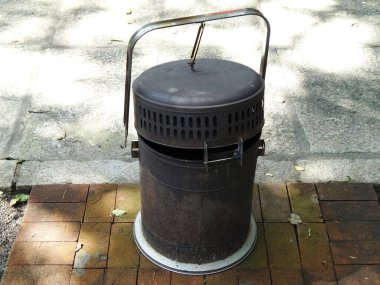Dışarıdaki tuğla kaldırımda duran eski metal çöp tenekesi
