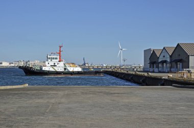Kargo gemisi sakin mavi suyun yanındaki depolara yanaşıyor.