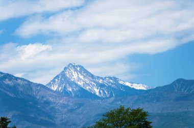 Güzel karla kaplı dağ zirveleri ve mavi gökyüzündeki bulutlar