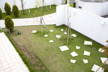 Dağınık beyaz kiremitleri olan yeşil çimlerin havadan görünüşü