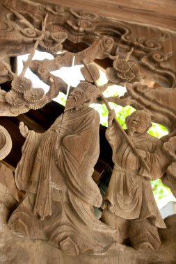 Karmaşık ahşap işçiliği, canlı bir ortamda kültürel bir kutlama sırasında geleneksel giysiler içinde tarihi figürler tasvir ediyor.