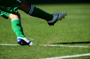 Spor giyim sektöründe futbol oyuncusunun bacakları çimlerin üzerinde top oynuyor.                 