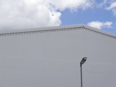 Beyaz sanayi binasının çatısı mavi bulutlu arka planla buluşuyor