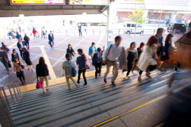 Şehirde merdivenlerden inip çıkan kalabalığın hareketli görüntüsü bulanık.   