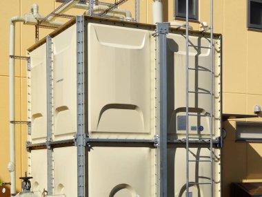 Sarı bina duvarına karşı büyük bej depolama tankı