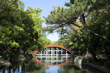 Japonya 'daki parkta yeşil ağaçlarla güzel bir köprü.