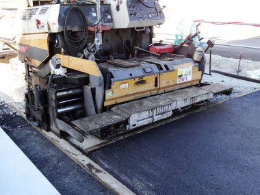 İnşaat sahasına asfalt döşeyen ağır makineler.